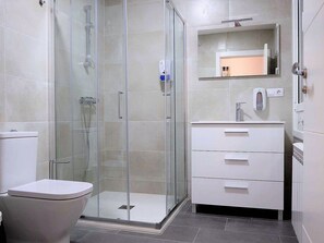 A modern bathroom with a glass-enclosed shower, a white toilet, and a vanity with a mirror and a soap dispenser. - Belvilla by OYO Villa Trabazos Abellas (Ourense)