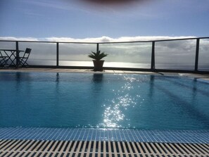 An infinity pool with a view of the ocean, a potted plant, and a table with chairs. - Vista do Mar Comfortable Holiday Residence (Calheta)