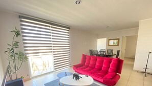 A modern living room with a red sofa, a white coffee table, and a potted plant. - Alojamiento en Yecapixtla, Morelos. Disfruta con Amigos o Familia! (Yecapixtla)