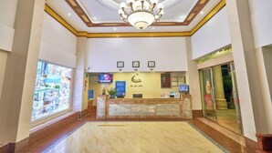 A hotel reception area with a chandelier, a reception desk, a digital display, and a large window. - Xiachuan Island Haijiao Hotel (Taishan)