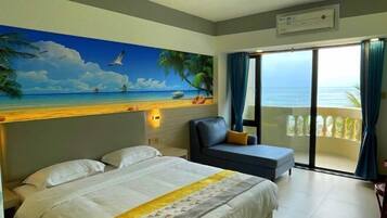 A hotel room with a bed, a sofa, a painting of a beach scene, and a balcony with a view of the ocean.
