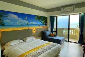 Habitación de hotel con cama, sofá, un cuadro de una playa y balcón con vista al océano.