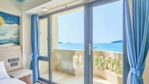 A room with a bed, a large sliding glass door leading to a balcony with a view of the sea. - Xiachuan Island Haijiao Hotel (Taishan)