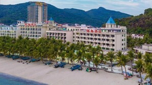 A beachfront hotel with multiple buildings, palm trees, and a mountain backdrop. - Xiachuan Island Haijiao Hotel (Taishan)