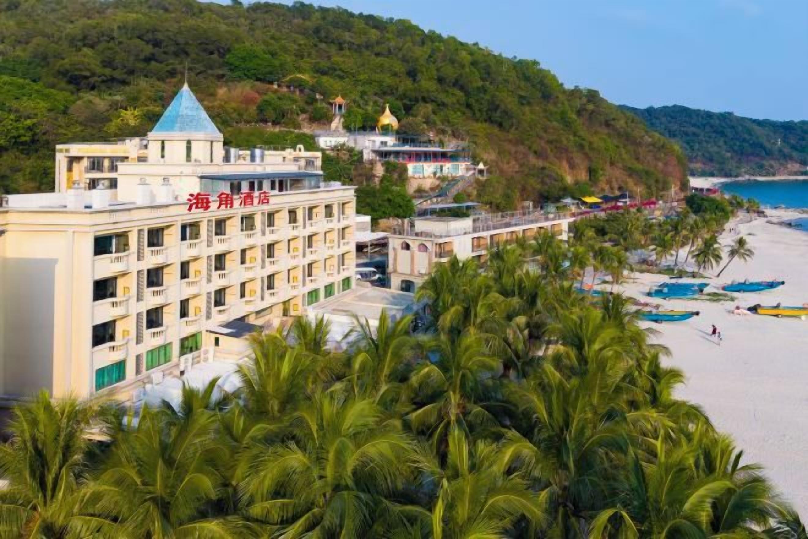 A hotel with multiple floors, a beach, and palm trees.