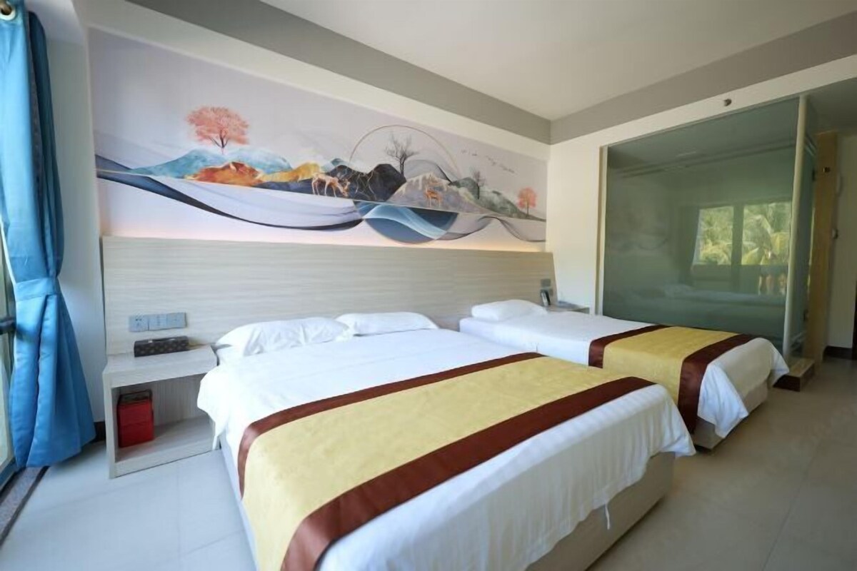 Una habitación de hotel con dos camas, un cuadro en la pared, un escritorio con lámpara y una puerta corredera al exterior.