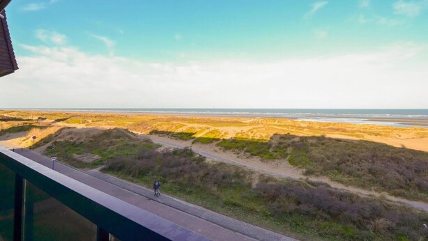 A coastal landscape with a road leading to the beach, viewed from a balcony.