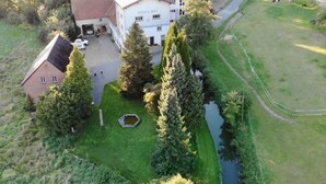 An aerial view of a large building with a white facade and a red roof, surrounded by lush greenery and a small pond. - Spacious Holiday Home in the Teutoburg Forest (Schieder-Schwalenberg)