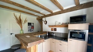 A kitchen with wooden beams, a bar counter, stools, a microwave, and an oven. - Spacious Holiday Home in the Teutoburg Forest (Schieder-Schwalenberg)