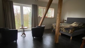 A bedroom with a bed, two armchairs, a small table, and a window with curtains. - Spacious Holiday Home in the Teutoburg Forest (Schieder-Schwalenberg)