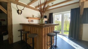A rustic kitchen with wooden beams, a bar area with stools, and a large window with curtains. - Spacious Holiday Home in the Teutoburg Forest (Schieder-Schwalenberg)