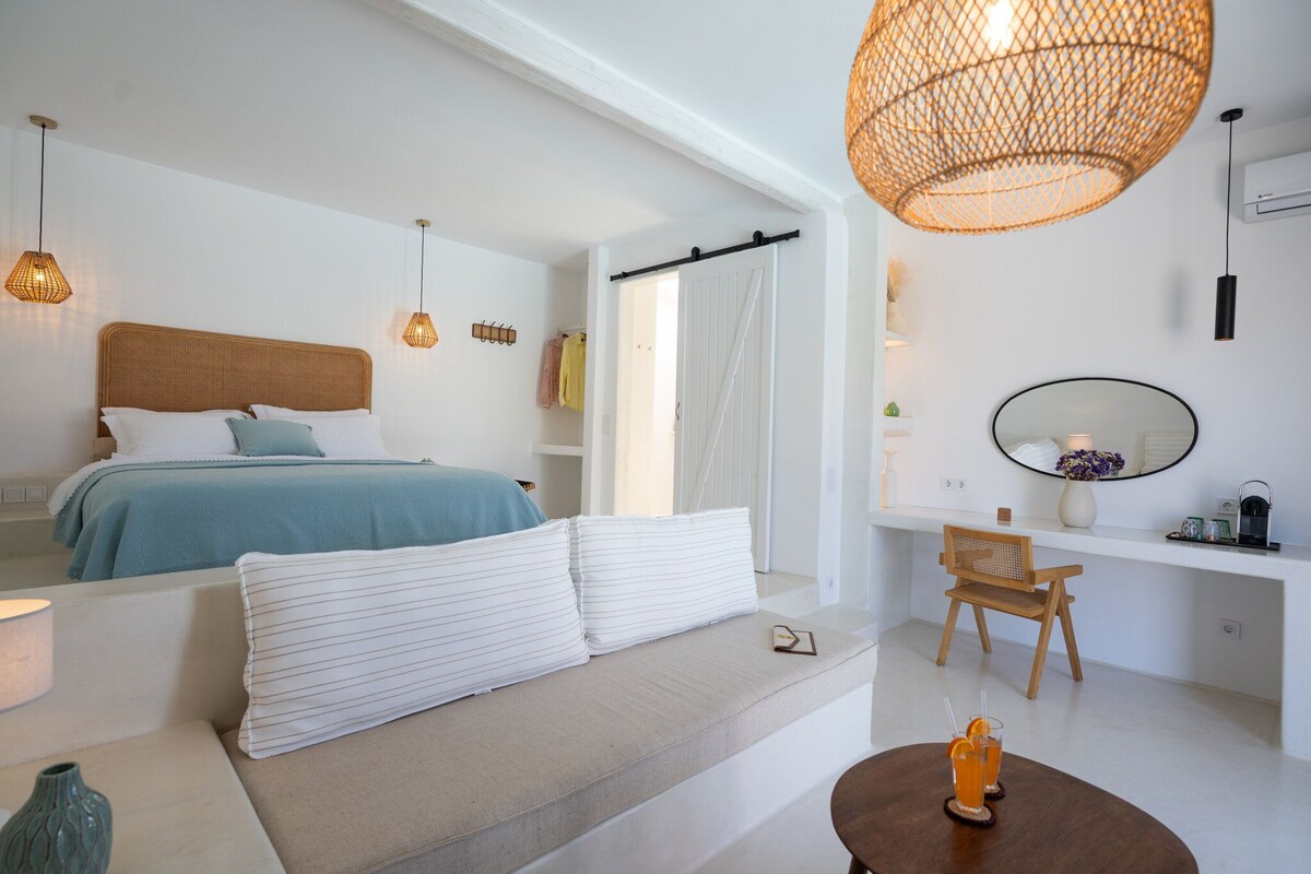 A modern bedroom with a bed, bedside table, and a seating area with a table.