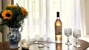 Una mesa con un jarrón de girasoles, una botella de vino, dos copas de vino y una figura decorativa de soldado de hojalata.
