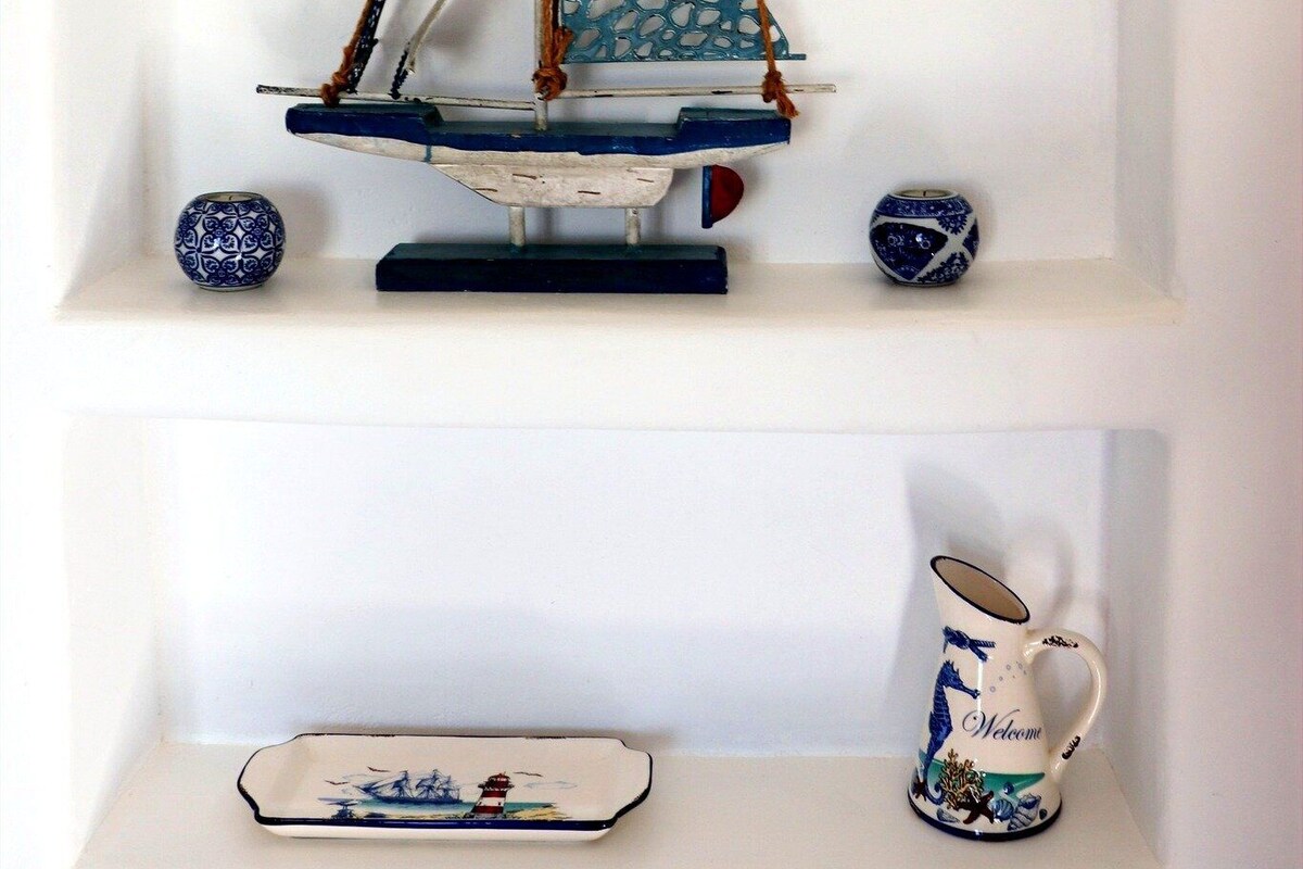 Un modèle de voilier est posé sur une étagère, avec des objets décoratifs en dessous.