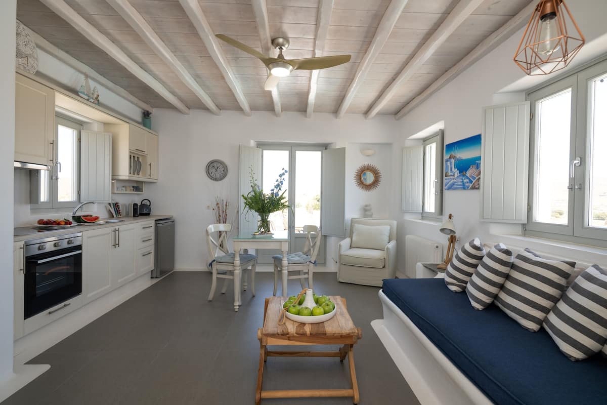 A modern kitchen with white cabinetry, a dining table, and a blue sofa with striped pillows.
