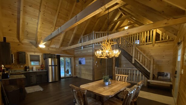 Un intérieur rustique en bois comprenant un coin repas, une cuisine et un escalier.