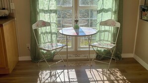 Ein Zimmer mit einem großen Bogenfenster, zwei Stühlen, einem Tisch und einem grünen Vorhang.