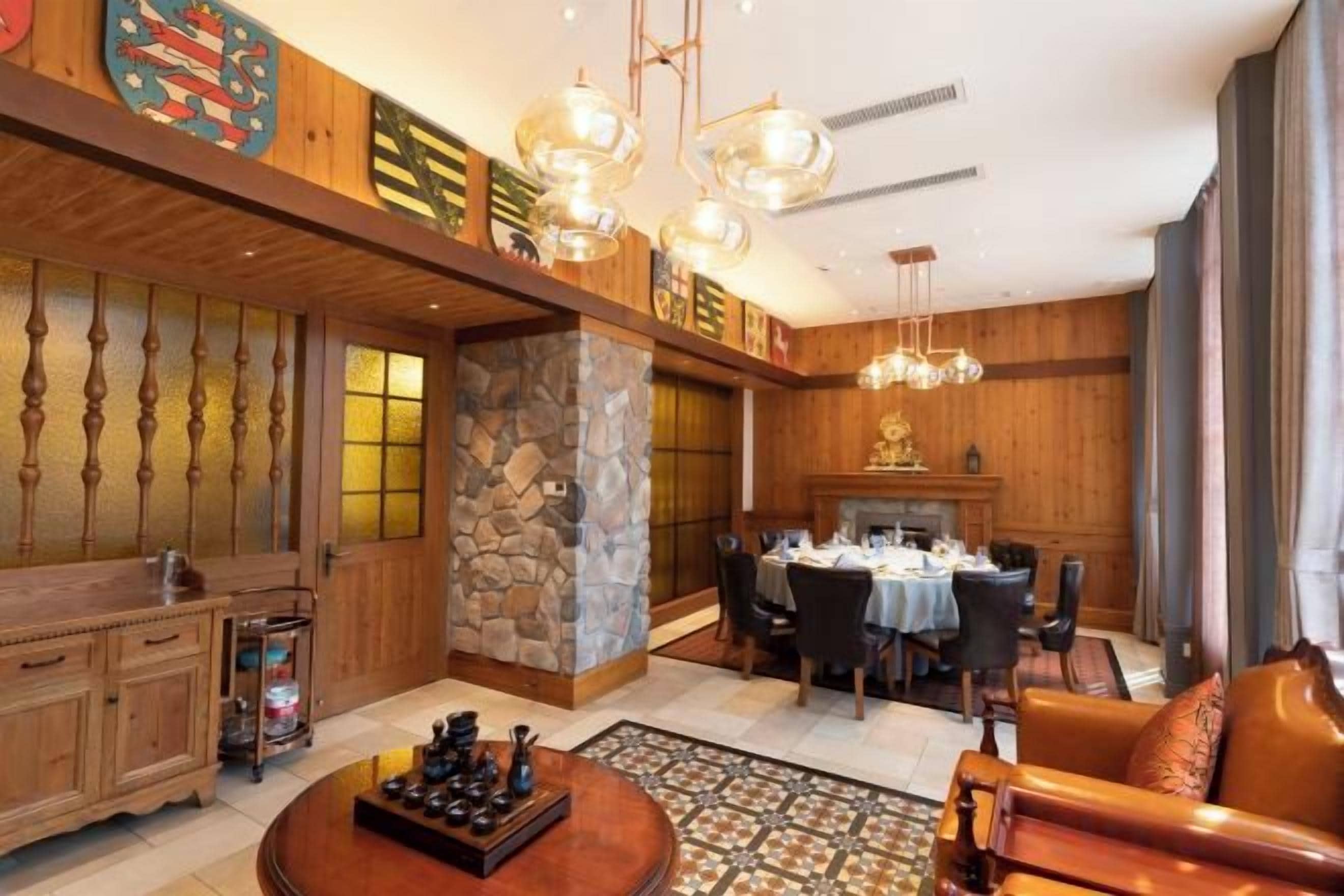 A spacious living room with a dining area, wooden paneling, stone accents, and a fireplace.