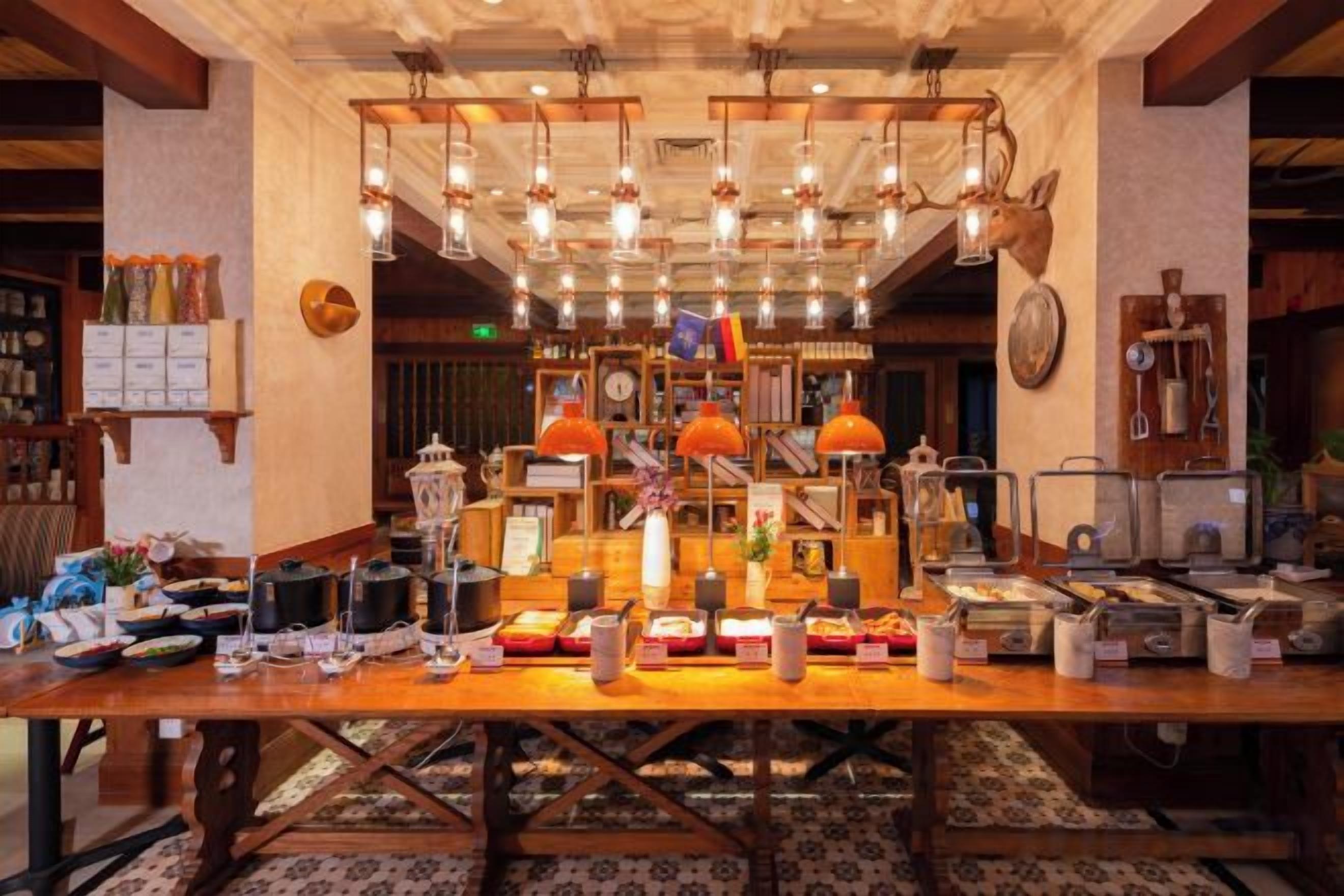 Un vestíbulo de hotel con una larga mesa de recepción, varias lámparas colgantes y una variedad de objetos expuestos.