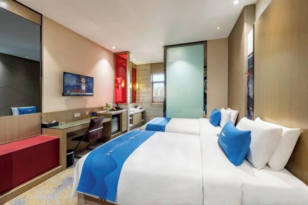 A hotel room with a bed, a desk, a chair, a TV, and a bathroom.