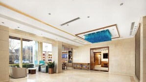 A spacious lobby with a reception desk, seating area, and a large window offering a view of the street. - Shunhe Tianxi Hotel (Jinan Station, Jinan Maternal & Child Health Hospital) (Jinan)