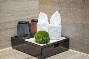 A modern bathroom with a dark wooden vanity, a glass jar, and two white towels on a white countertop.