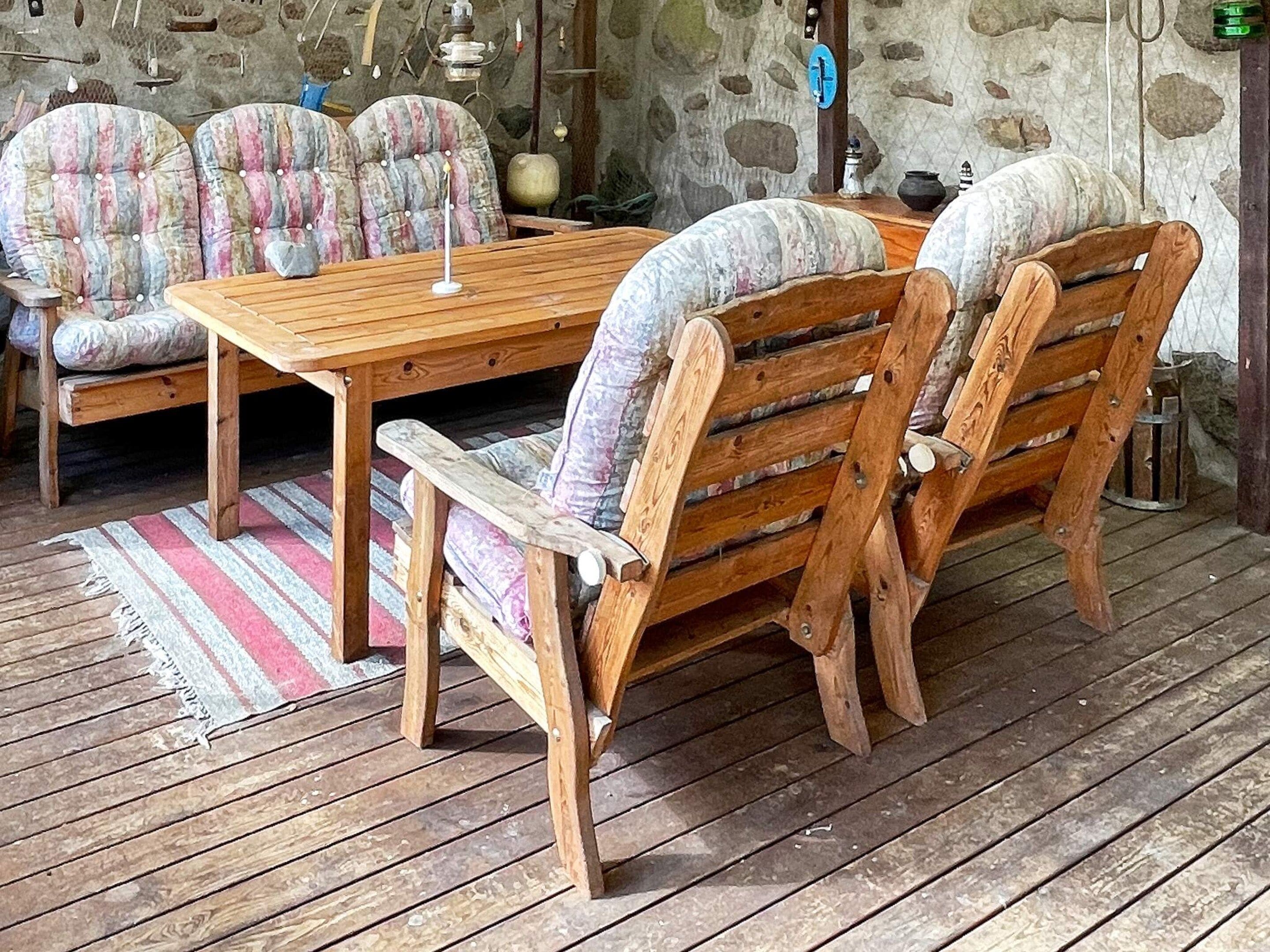 A rustic wooden table with chairs, a stone wall, and a wooden floor.