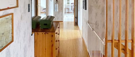 Un couloir avec un plancher en bois, un banc en bois et un radiateur sur le côté droit.