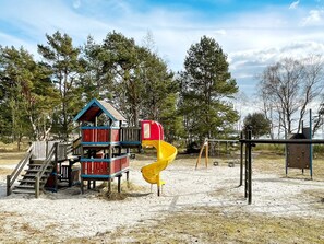 A playground with a slide and a wooden playhouse. - 4 Person Holiday Home in Solvesborg (Sölvesborg)
