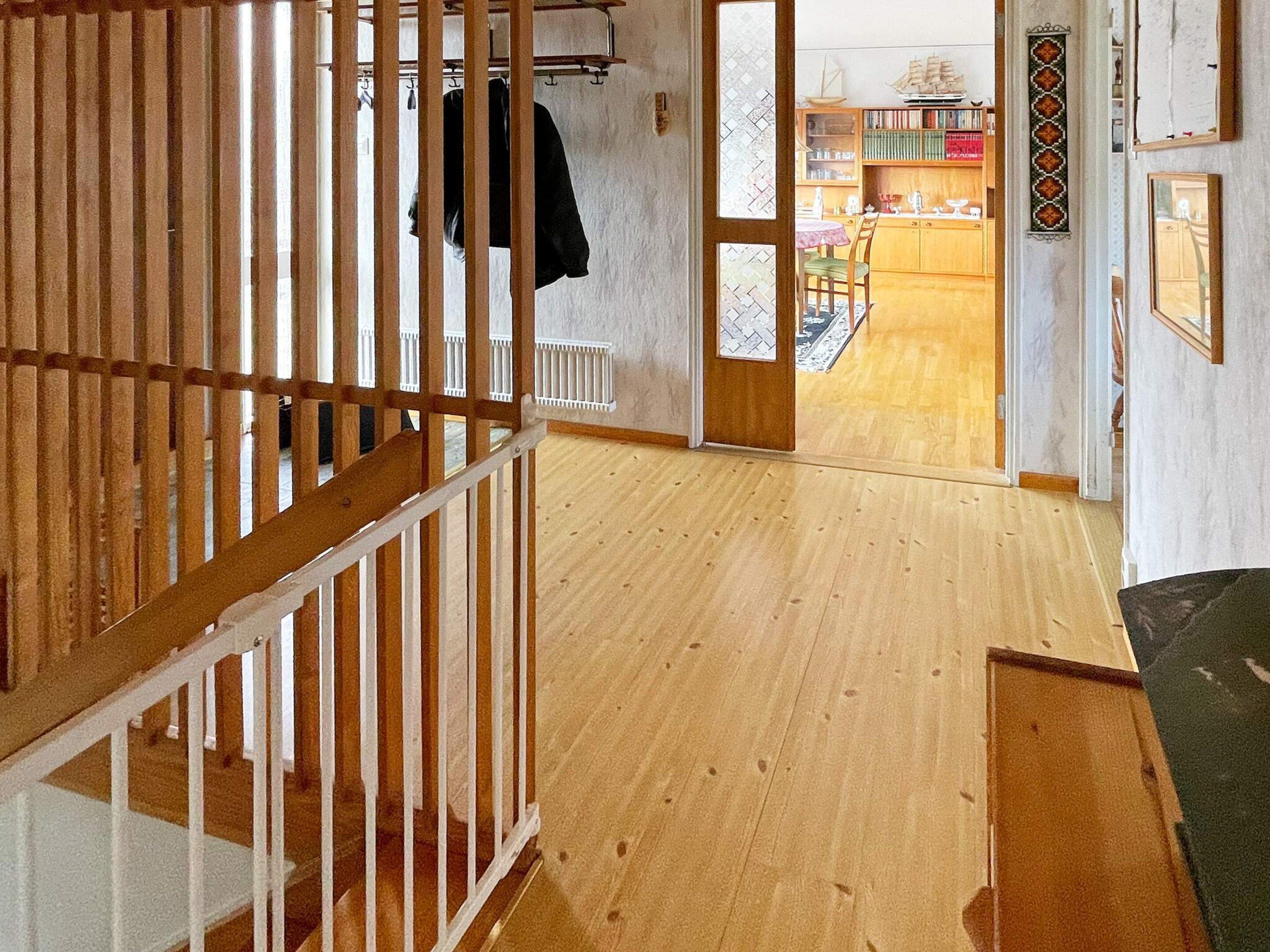 A wooden staircase leading to a room with a view of a dining area.