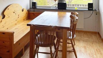 A wooden dining table with chairs, a bench, and a window with a view of trees.