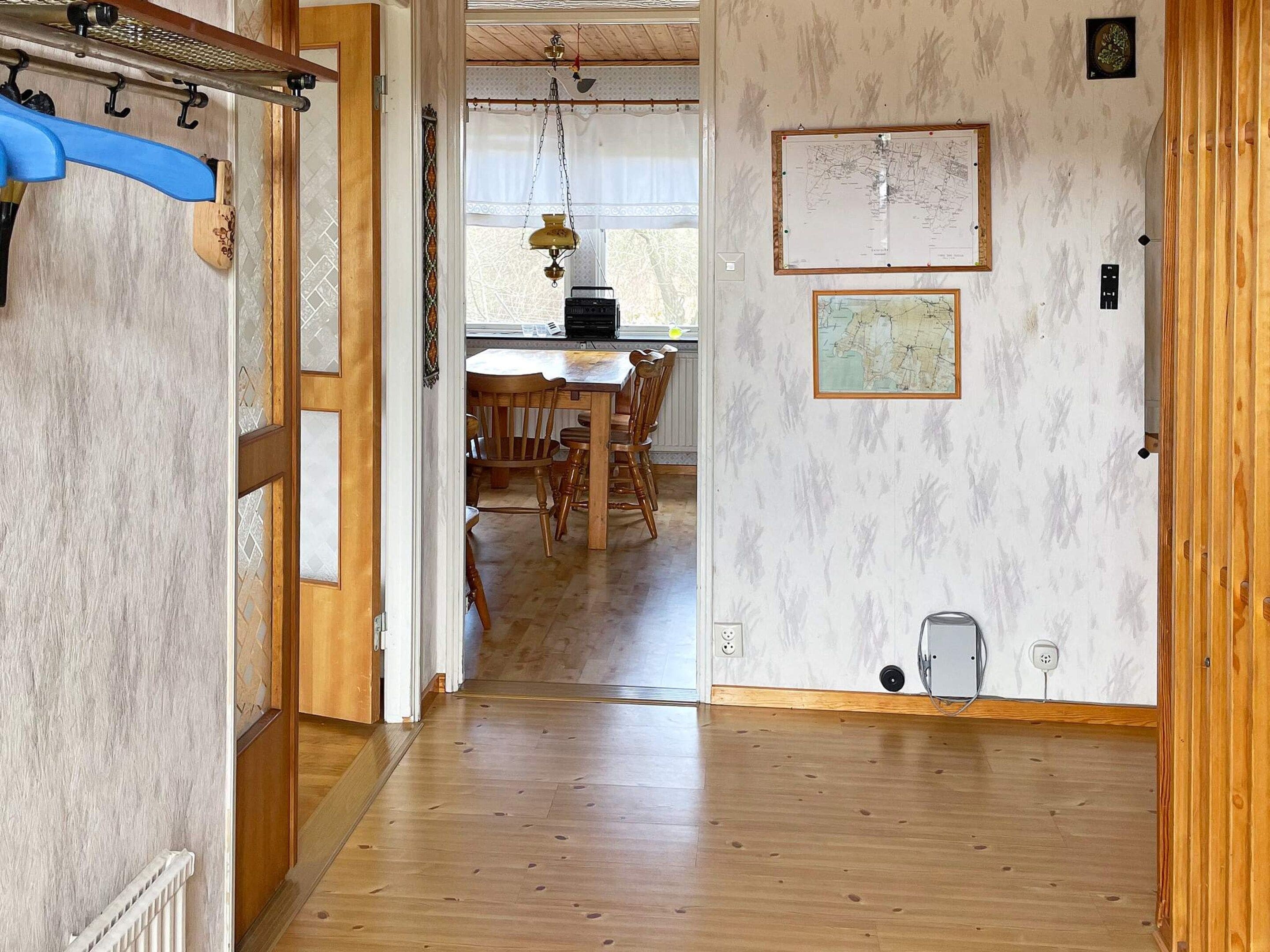A hallway leading to a dining area with a wooden table and chairs.
