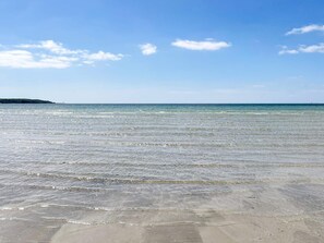 A beach with clear water and a distant landmass. - 4 Person Holiday Home in Solvesborg (Sölvesborg)
