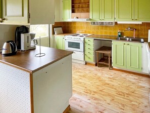 A kitchen with green cabinets, a stove, a sink, and a coffee maker. - 4 Person Holiday Home in Solvesborg (Sölvesborg)