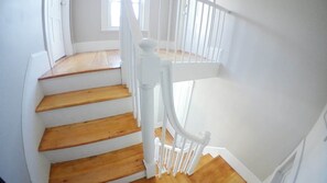 Una escalera con escalones de madera y barandillas blancas.