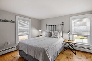 Un dormitorio con una cama grande, dos mesitas de noche con lámparas y una ventana con persianas.