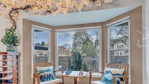 A corner room with large windows, a wooden chair, a small table, and a decorative plant. - Immersive Spa Retreat — A Fantasy Smart Home (Lakewood)