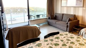 A hotel room with a large sliding glass door to a balcony, a sofa, a small table, and a bed with a leaf-patterned bedspread. - Apartment in Nieuwpoort by the Beach (Nieuwpoort)
