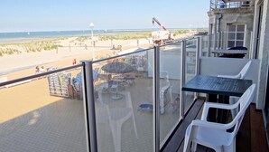 A balcony with a view of the beach, outdoor seating, and a crane in the background. - Apartment in Nieuwpoort by the Beach (Nieuwpoort)