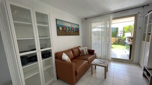 A living room with a brown leather sofa, a glass cabinet, and a painting on the wall.