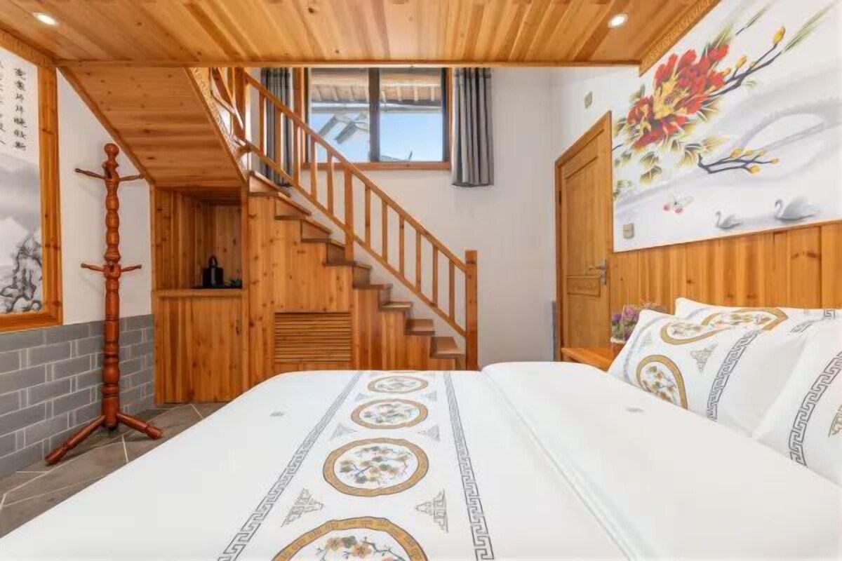 Un dormitorio con cama, paredes de madera, una escalera y un cuadro en la pared.