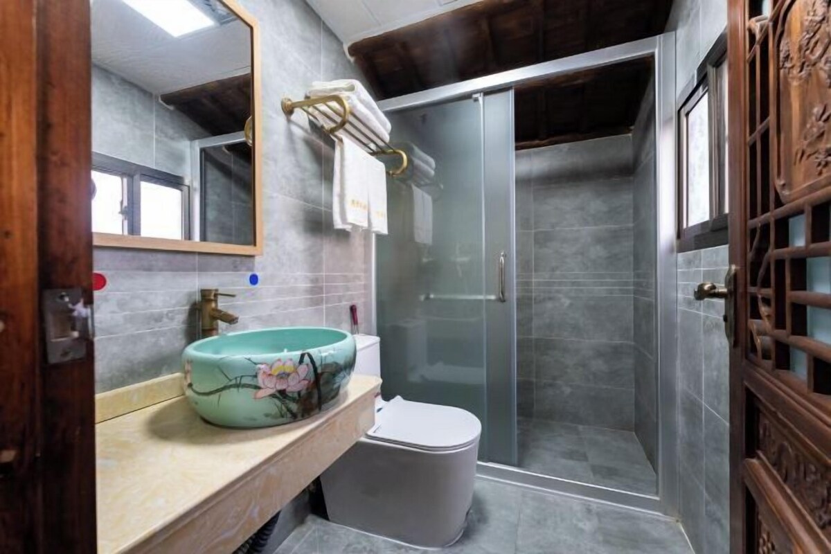 Un baño con cabina de ducha de vidrio, lavabo con recipiente decorativo e inodoro.