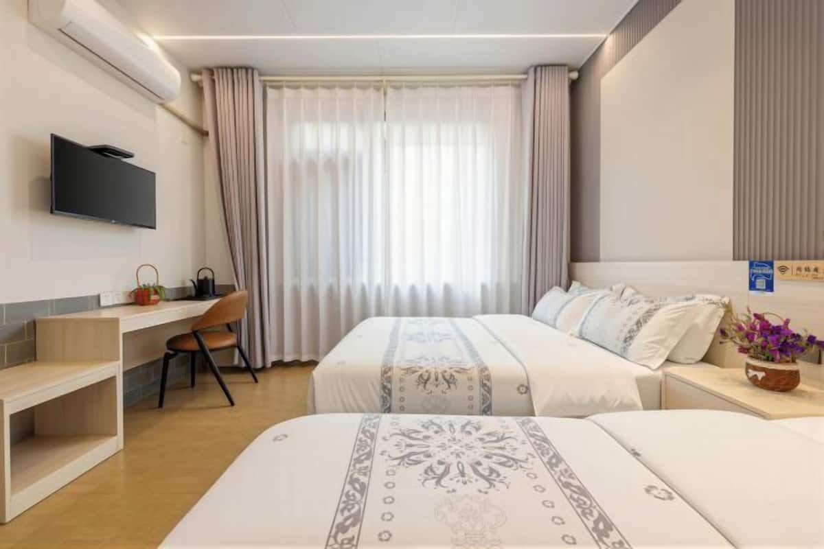 Une chambre d’hôtel avec deux lits, un bureau, une télévision et une fenêtre avec des rideaux.