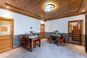 Una habitación con techo de madera, una mesa de comedor con sillas y una escalera que lleva a otro nivel.