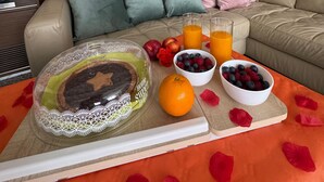 A cozy living room with a brick wall, a large mirror, a beige sofa, and a breakfast setup on a wooden table. - The Owl's Den (San Paolo Solbrito)