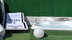 Ein Wellnessbereich mit Whirlpool, Kunstrasen und weißen Dekoelementen.