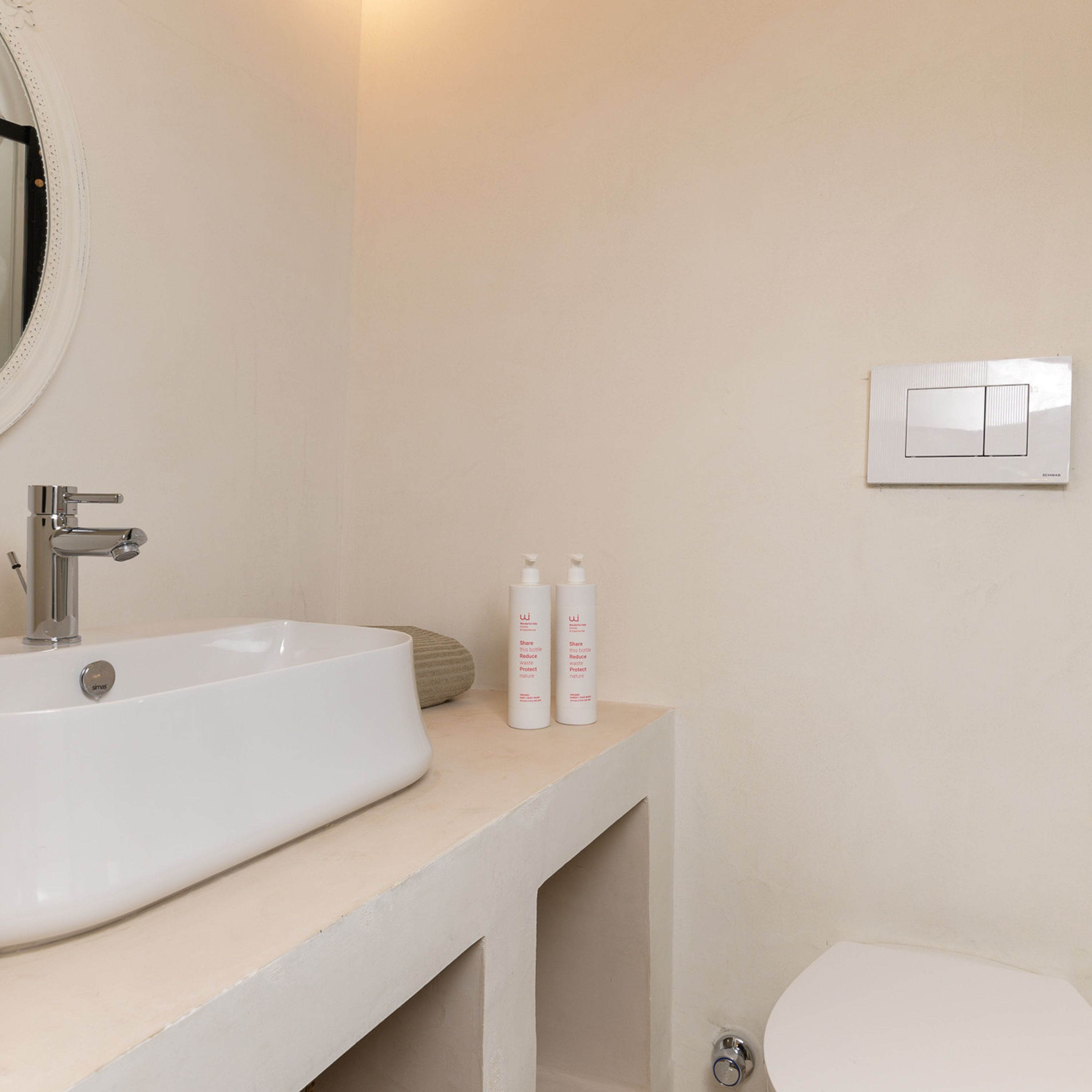 A bathroom with a white sink, a mirror, and two bottles of toiletries on the countertop.