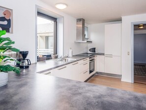 A modern kitchen with white cabinets, a built-in oven, a microwave, and a coffee maker.