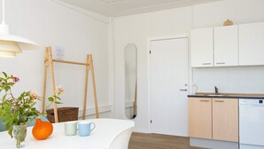 A modern kitchen with white cabinets, a wooden floor, and a dining area with a white table and chairs. - 10 Person Holiday Park Home in Ulfborg (Ulfborg)