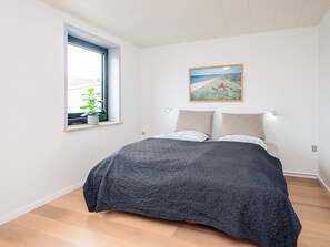 A bedroom with a bed, a window with a plant, and a painting on the wall. - 10 Person Holiday Park Home in Ulfborg (Ulfborg)
